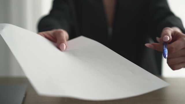 A female boss hands over documents for signing.
Paper contract. Signing documents.