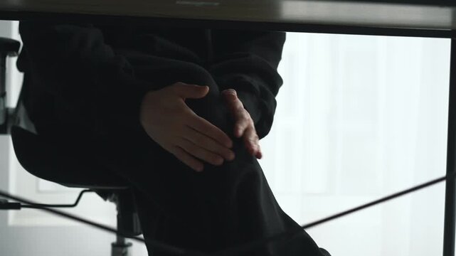 Anxiety at work.
First day at work.
Legs tremble from fear.
Man clutches his shaking knees.