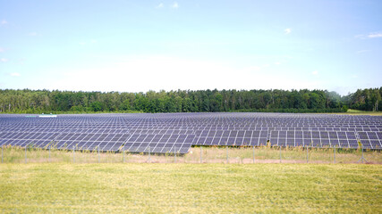 Wide view of photovoltaic solar panels in rural field on sunny day © Moiseii Production