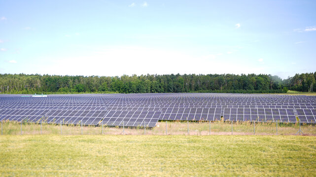 Wide view of photovoltaic solar panels in rural field on sunny day