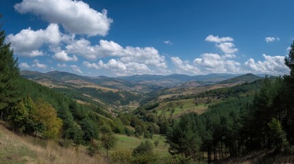 Breathtaking Panoramic View of Serene Mountain Landscape with Lush Green Valley Under Blue Sky and Fluffy White Clouds in Autumn Season