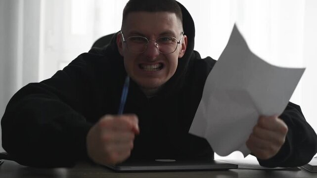 An angry office worker at his computer desk.
The man is yelling and angry.
The guy in the black sweater is angry.