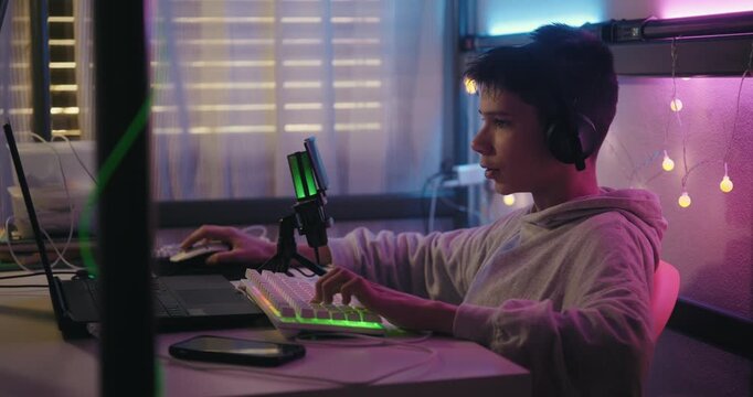 Teenage Boy Gamer Playing Online Video Game on a Computer at Night