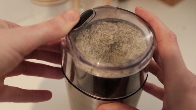 Close-up of green pumpkin seeds being ground into a fine powder or meal. This footage highlights healthy superfood preparation, organic nutrition, vegan protein sources, and the texture of raw pumpkin