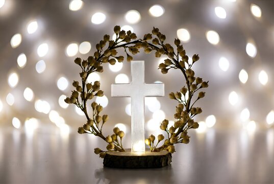 Croix en bois blanc entour&eacute;e de lumi&egrave;res scintillantes et fleurs, symbole de la croix chr&eacute;tienne pour P&acirc;ques et communion