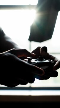 Gaming Hands Silhouette Holding Controller Near Window Sunlight.