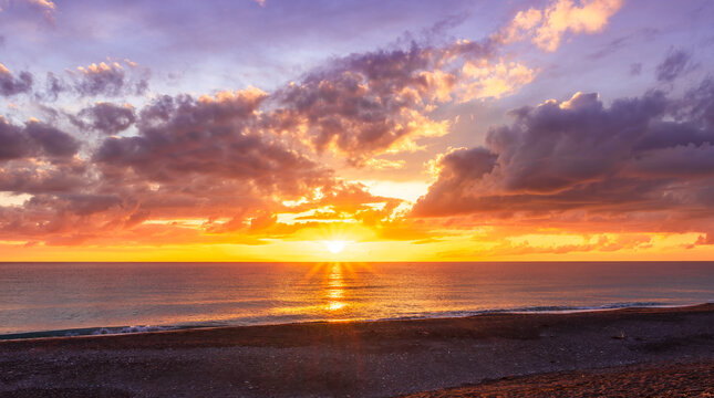 Dramatic seascape of sunset or sunrise sky with clouds during morning or evening. Dramatic sunset over the sea with orange clouds and sun above ocean water