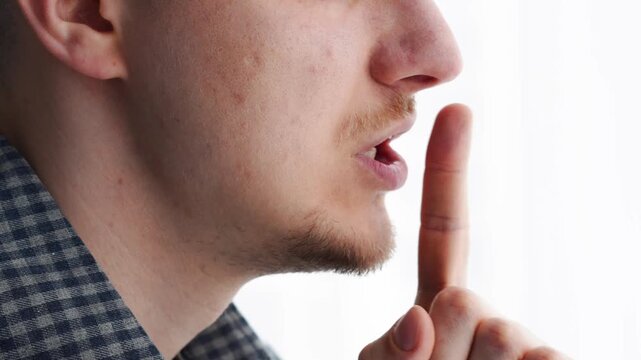 The silence sign "shh"
A man gestures with his finger to keep quiet and not talk.