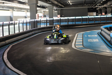 Racers navigate sharp curves in a competitive indoor go-karting facility, showcasing skill. © Dejan