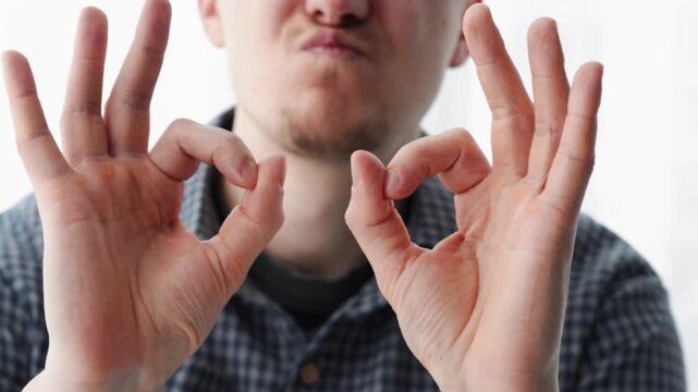 A happy man shows that everything is fine. Everything is great.
Okay with his fingers.
Body language.