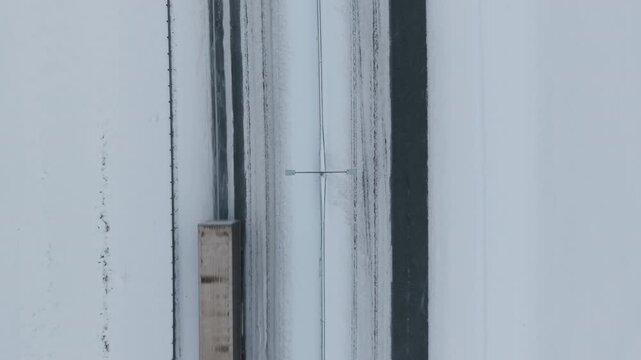 Blue truck runs alongside snowy tracks. Freight vehicles process through icy winter landscape efficiently