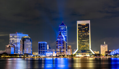 Obraz premium Jacksonville, Florida downtown skyline at night. Scenic view features illuminated skyscrapers including the Wells Fargo Center and Bank of America Tower reflecting in the St. Johns River