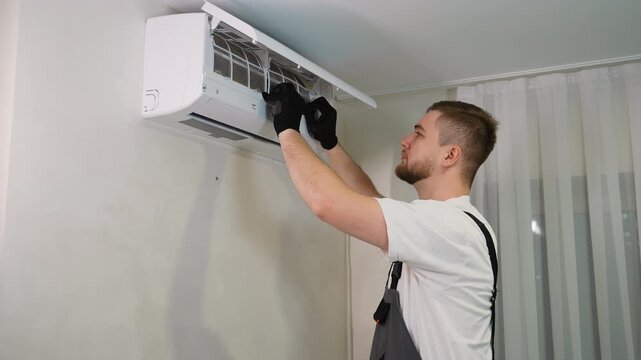 Male technician removing dirty air conditioner filter