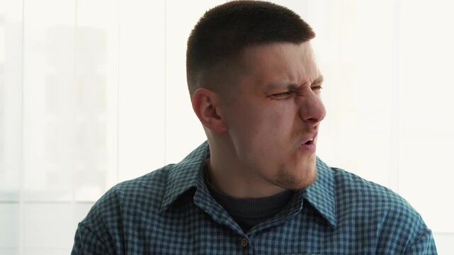 A man tears a piece of duct tape from his mouth.
The skin is stuck together from the duct tape.