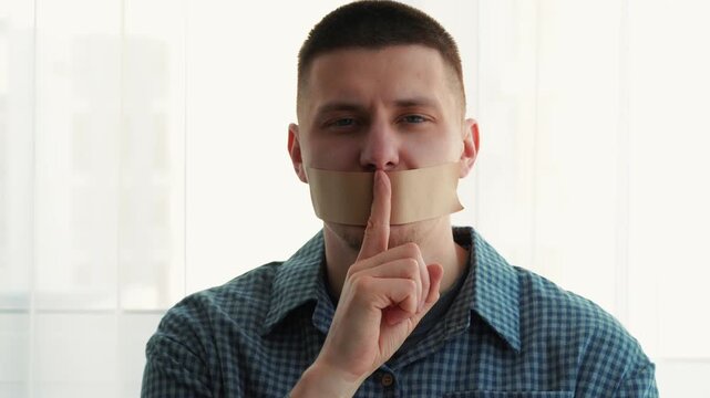 A man with duct tape over his mouth.
A gesture of silence.
Keeping secrets.
Portrait of a man with duct tape over his face.