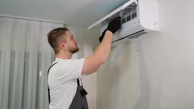 Air conditioner technician servicing indoor unit filter