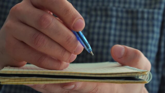 Writing the script with a pen in a notebook.
A screenwriter writes a script on paper.