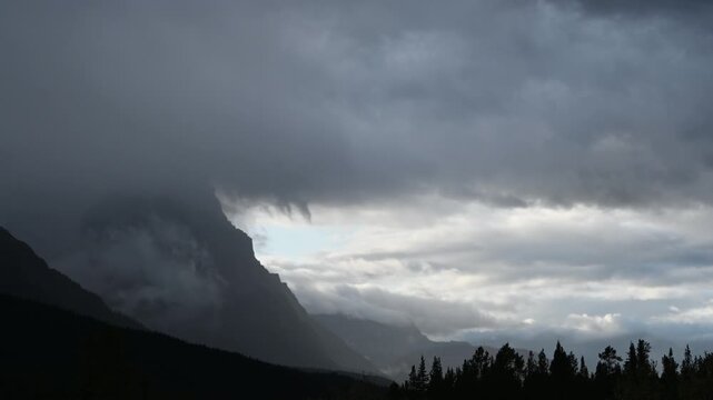 Late-day storm clouds sweep across the sky in a dramatic time-lapse, rolling above distant hills silhouetted against fading evening light.