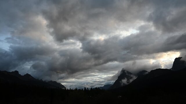 Low storm clouds churn and race across the sky in a moody time-lapse, drifting above distant mountain peaks silhouetted on the horizon.
