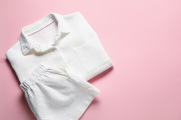 Trendy white pajamas on pink background, top view. Space for text