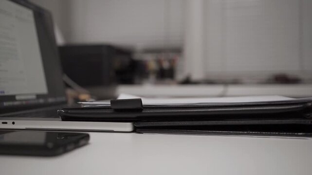 Medium shot of hand writing notes in notepad at desk. Concept of planning, organization and productivity in modern workspace.
