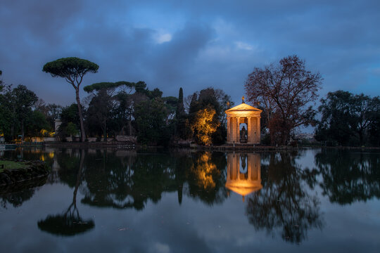 Panorama di alberi e tempio illuminato riflesso nel lago all'alba