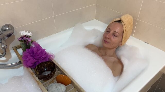Mujer relajada con ojos cerrados disfrutando un ba&ntilde;o de espuma