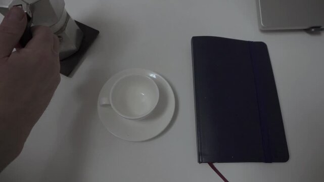 Overhead view of freelancer writing business plan in notebook with coffee on desk. Concept of entrepreneurship, goal setting and remote work lifestyle.