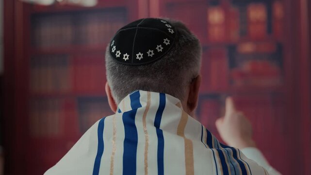 jewish Men from the back, head is covered by a traditional jewish kippah with blue and gold stripes and tassels. Close up view