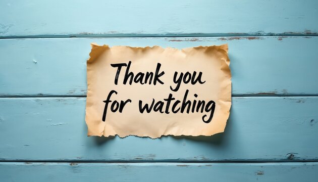Torn paper note with handwritten phrase thank you for watching rests on weathered blue wood planks. Simple background for video end screens presentations or social media content.