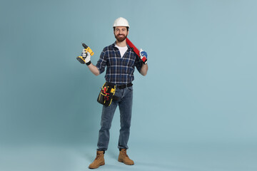 Naklejka premium Professional builder with different tools on light blue background