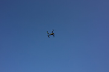 Modern aerial drone flying in clear blue sky capturing video of urban festivals and public celebrations. Advanced technology, media production and city entertainment coverage