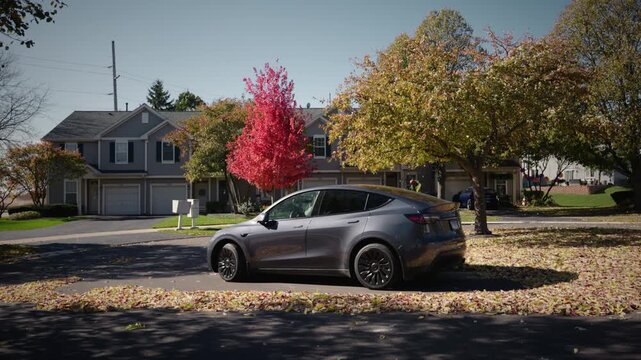 Quiet suburban neighborhood street with parked car and colorful autumn trees, peaceful residential street in fall season.