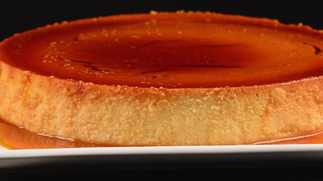 Cream cheese flan with a layer of liquid caramel, dessert slowly rotating on a rotating base