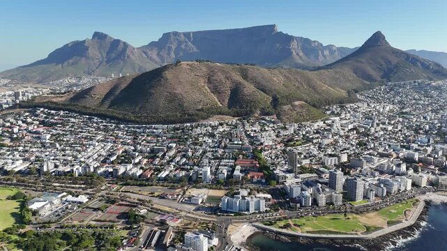 Drone lowers over water with iconic view of city on a sunny day in Green Point, Cape Town, South Africa