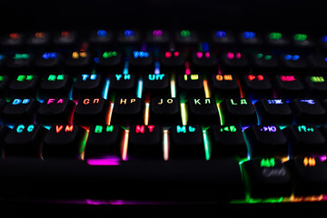 Colorful RGB keyboard glowing in dark room with vivid multicolor backlight, creating dynamic cyber gaming atmosphere and modern digital technology background scene