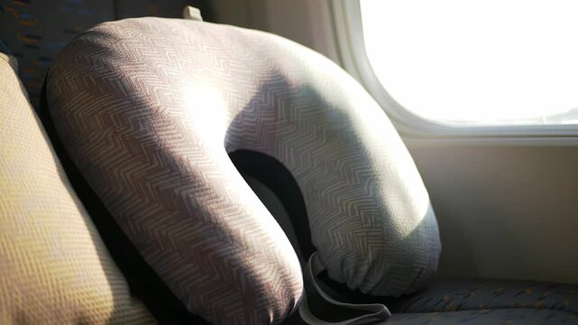 Travel pillow on train seat near window, promoting comfort, relaxation, travel.