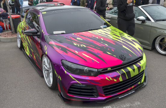Striking Volkswagen Scirocco, prime example of modern automotive culture and self expression, captivates with an aggressive stance and a vibrant, one off custom wrap