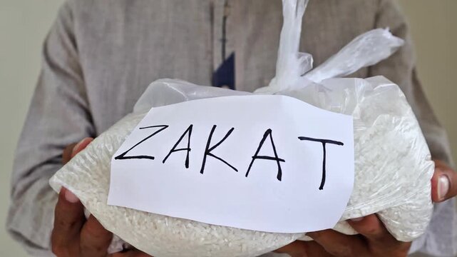 Muslim man hands over zakat fitrah rice