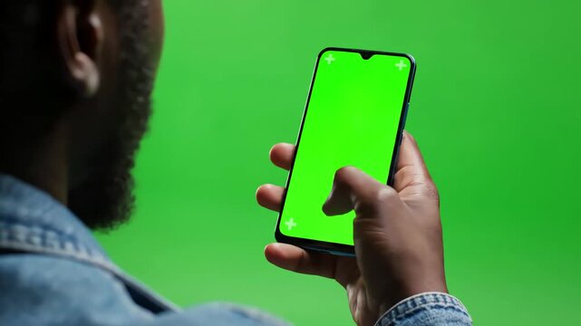 Green Screen close up shot of head and hand afro american man holding his smartphone with looking on it scrolling touching backside view mock scene 3 distortion, overlay, glitch, static noise, scan