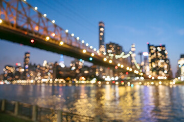 Soft colorful lights from the Queensboro Bridge and Manhattan skyline blur together in a dreamy bokeh scene. Reflections shimmer across the East River, creating an artistic and atmospheric city view.