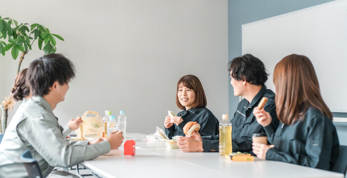 Businessmen and women in work clothes eating lunch in the break room