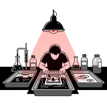 Illustration of a person developing film in a darkroom with trays and a red safety light