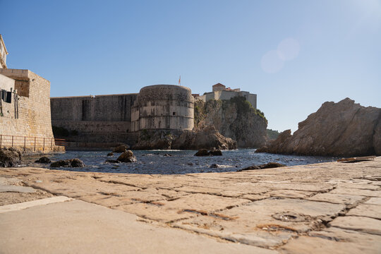 Epic Dubrovnik Fort Bokar ancient fortress city walls panorama. 
Cinematic view of historic Lovrijenac castle on rocky cliff, 
old town stone bastions and blue Adriatic sea water in Croatia.
