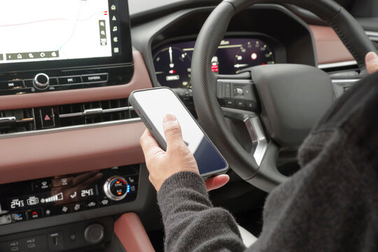 運転席でスマホを操作している男性の手元