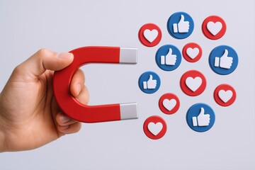 Hand Holding Magnet Attracting Social Media Likes and Hearts, Concept of Online Influence and Engagement