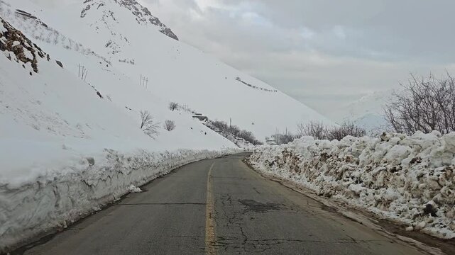 A narrow snow-covered mountain road winding between tall snowbanks and distant snowy peaks under a cold, overcast winter sky.
📍Hawraman Takht, Kurdistan 