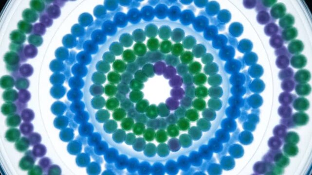 Abstract circular pattern of colorful beads in shades of blue, green, and purple, creating a mesmerizing, hypnotic visual effect