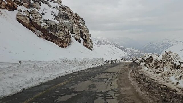 A twisting snow-covered mountain road bordered by high snow walls, winding through snowy hills and rugged peaks under a cold, overcast winter sky.
📍Hawraman Takht, Kurdistan 