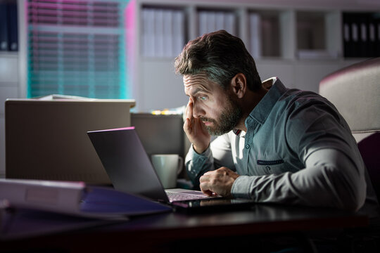 Tired businessman working late at night on laptop in office. Business problem. Overworked manager with headache. Overworked business manager. Stressed employee with anxiety with deadline. Dry eyes